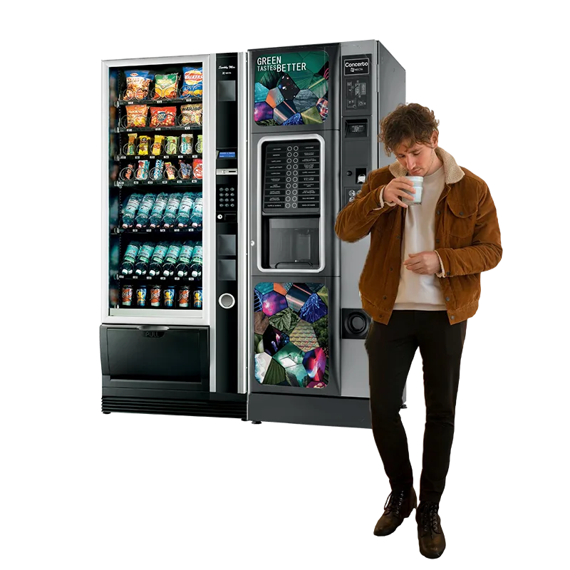 Un employé boit un une boisson chaude devant des distributeurs automatiques de chez FABAUR CAFÉ dans la Drôme.